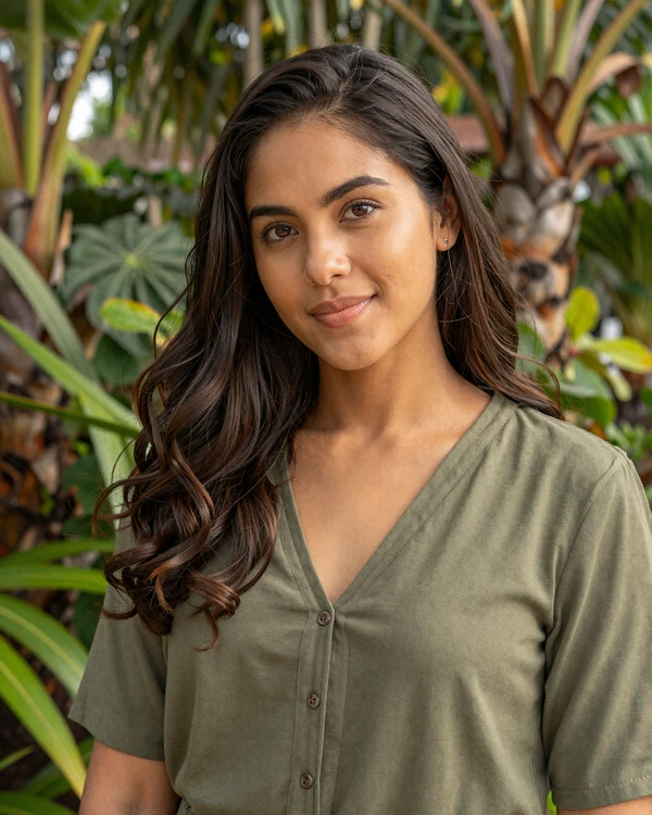 Beautiful Honduran woman smiling warmly in a tropical garden setting - authentic Honduran dating culture and genuine Latina warmth